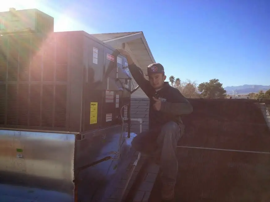 HVAC technician performing AC Tune-Up on a rooftop unit in Newcastle